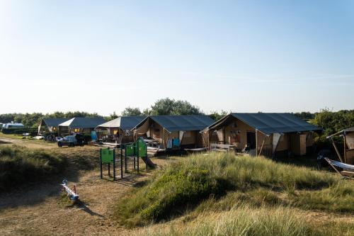 a group of tents in a field with a playground at Glamping Ameland in Buren