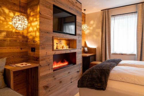 a bedroom with a fireplace and a tv on a wall at Araldo Eco-Lodge in Bosco Chiesanuova