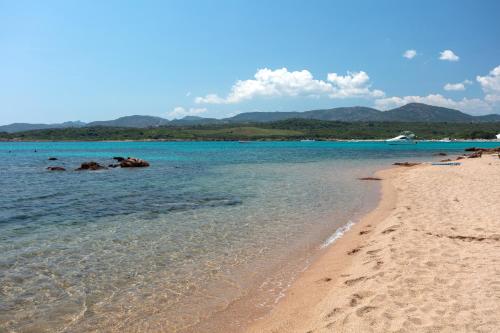 a beach with the ocean and mountains in the background at Baia Dorata beach apartments in Porto Istana