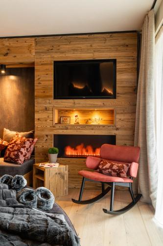 a living room with a fireplace with a tv on a wall at Araldo Eco-Lodge in Bosco Chiesanuova