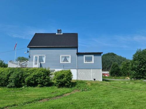 a gray house with a black roof on a green field at Koselig hus med hage i Herøy på Sunnmøre. in Røyra