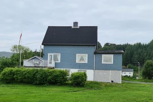 a blue house with a balcony on a green field at Koselig hus med hage i Herøy på Sunnmøre. 