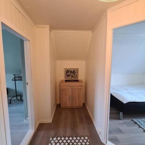a small room with a bed and a wooden cabinet at Koselig hus med hage i Herøy på Sunnmøre. in Røyra