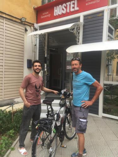 deux hommes debout devant un bâtiment avec un vélo dans l'établissement Hostel 5 Сapsule - rooms, à Öskemen