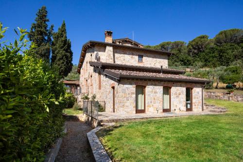 an old stone building in a field with a yard at Fattoria Le Fonti in Poggibonsi