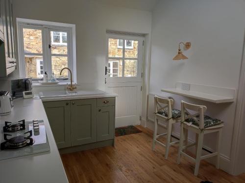 a kitchen with a sink and a counter with two chairs at Tree Fern Barn in St Austell