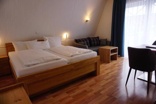 a bedroom with a bed and a chair and a table at Hotel Pension Julia in Norddeich