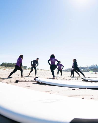 a group of people walking on the beach with surfboards at Apartamentos Costa Norte in San Vicente de la Barquera