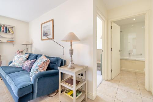 a living room with a blue couch and a lamp at Fig Cottage in Eastdean