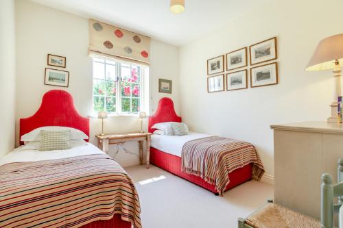 two beds in a room with red chairs at Fig Cottage in Eastdean