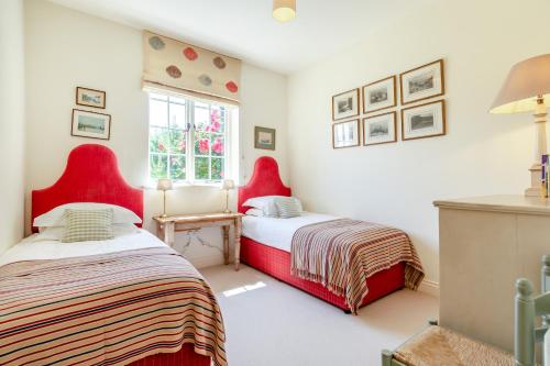 2 camas en una habitación con sillas rojas en Fig Cottage, en East Dean