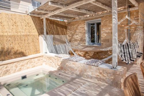 a patio with a hot tub and two chairs at TERRA E SOLE spa suite Aegina in Vathí