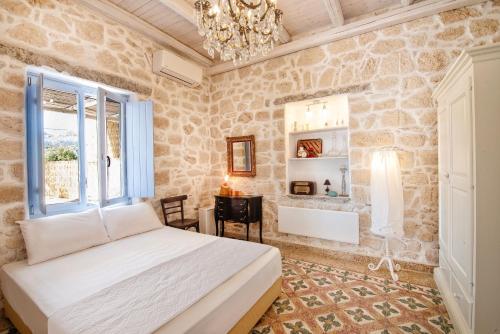 Schlafzimmer mit einem Bett, einem Schreibtisch und einem Kronleuchter in der Unterkunft TERRA E SOLE spa suite Aegina in Vathí