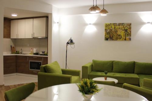 a living room with green couches and a kitchen at Domini LakeView Apartment in Mavrovo