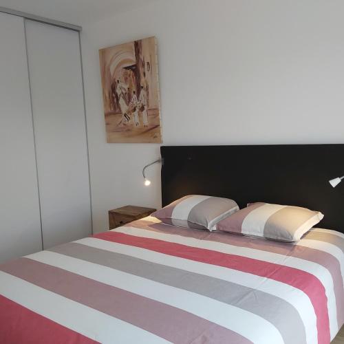 une chambre avec un lit avec une couverture rayée dans l'établissement Havre de Thairé, à Thairé