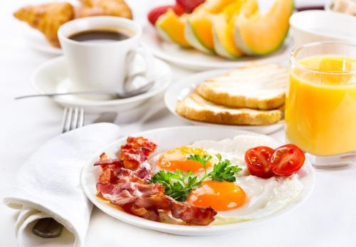 a plate of eggs bacon and toast and a glass of orange juice at Hotel City Pisek in Písek