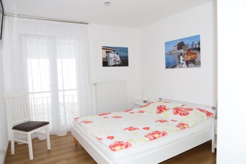 ランゲナルゲンにあるFeWo Bayha "Im blauen Haus"の白いベッドルーム(ベッド1台、椅子付)