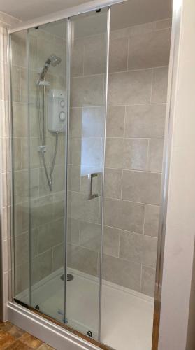 a shower with a glass door in a bathroom at Ashes Farm Cottage in Kilmington