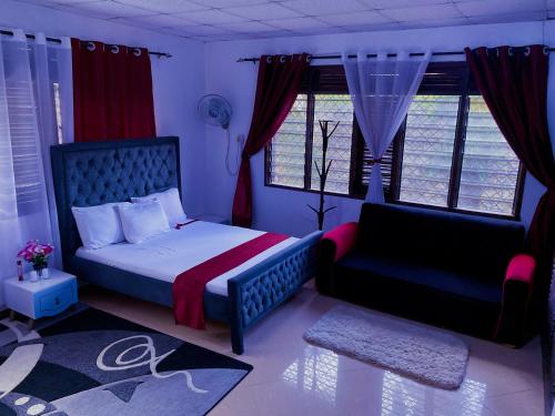 a bedroom with a bed and a chair and windows at Tinas Royal Cottage in Mombasa
