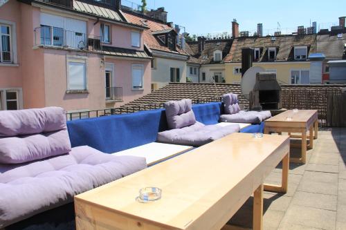 a row of couches and tables on a balcony at Stay2Night City Center Hostel in Zurich