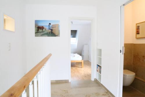 a white hallway with a stairway leading to a bathroom at FeWo Bayha "Im blauen Haus" in Langenargen