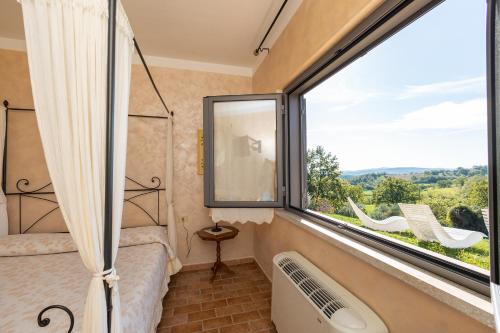 a room with a large window and a bed and a tub at Agriturismo La Meria in Semproniano