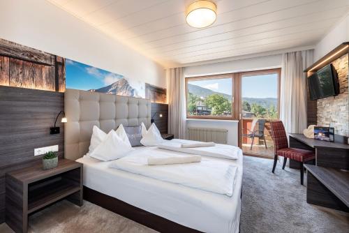 a bedroom with a large bed and a large window at Hotel Tyrol in Bressanone