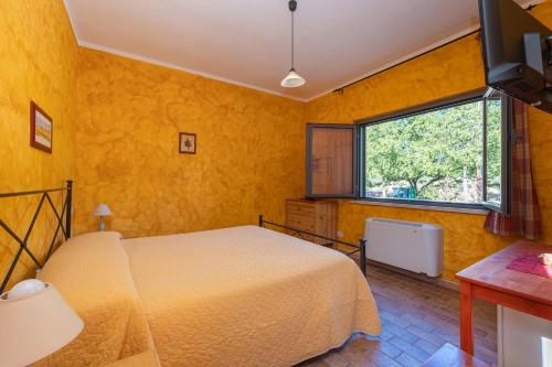 a yellow bedroom with a bed and a window at Agriturismo La Meria in Semproniano