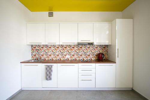 a kitchen with white cabinets and a yellow ceiling at Studio Świętojańska in Gdynia