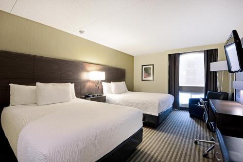 a hotel room with two beds and a flat screen tv at Victoria Inn Hotel and Convention Center Winnipeg in Winnipeg