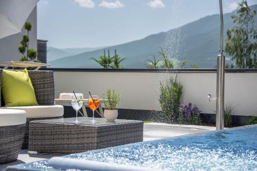 a patio with a swimming pool with two glasses of wine at Hotel Tyrol Plose in Bressanone