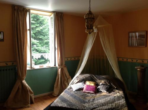 ein Schlafzimmer mit einem Himmelbett und einem Fenster in der Unterkunft MaisonMazerand in Cirey-sur-Vezouse