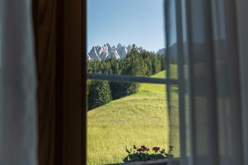 a window with a view of a green field and mountains at Hotel Villa Waldheim in San Candido