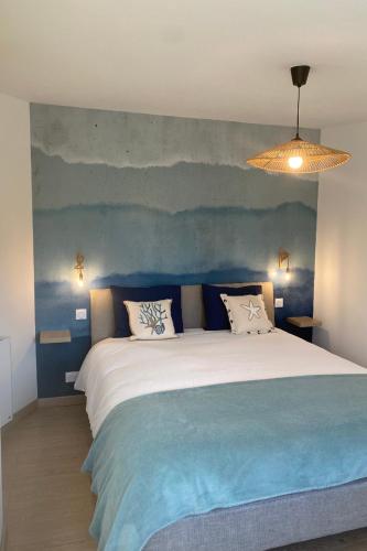 une chambre avec un grand lit avec un mur bleu dans l'établissement Le Gîte 55, à Paimpol