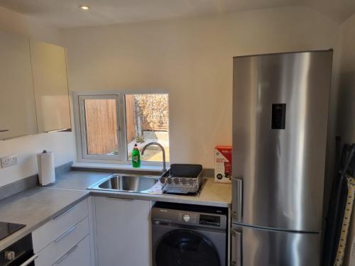 a kitchen with a stainless steel refrigerator and a sink at The Coppice-Private Studio Guest Suite With Private Entrance in Watford
