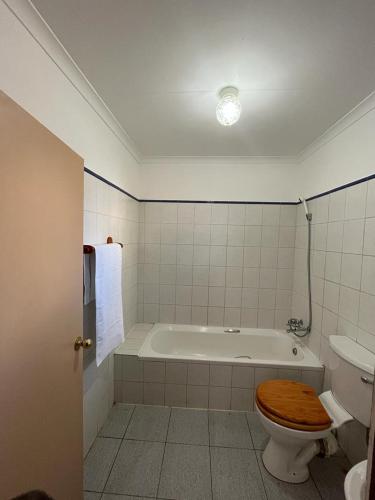 a bathroom with a tub and a toilet with a wooden seat at Ka Tembe Self Catering Lodge in Polokwane