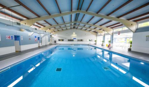 a large indoor swimming pool with blue water at STYLISH CHALET with SEA VIEWS at Kingsdown Park with Swimming POOL in Kingsdown