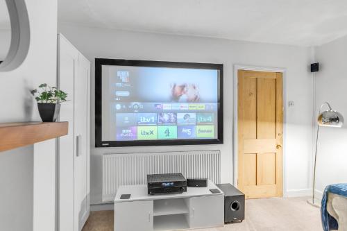 a living room with a flat screen tv on a wall at Sleeps 8 City House with Cinema Room and Parking in Norwich