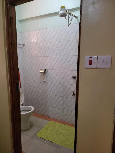 La salle de bains est pourvue d'une douche, de toilettes et d'un tapis vert. dans l'établissement G&G Westindies Executive One Bedroom, à Eldoret