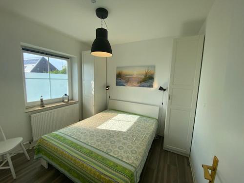 ein kleines Schlafzimmer mit einem Bett und einem Fenster in der Unterkunft Wulfen Auszeit & Meer Wulfen in Westfehmarn