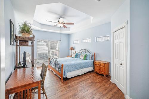 a bedroom with a bed and a desk and a ceiling fan at Villa Laguna! STEPS to the pool & lagoon views, with boardwalk to beach in Port Aransas