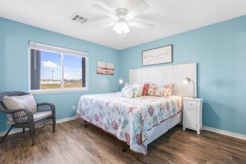 a bedroom with blue walls and a bed and a chair at Wave on Wave! Overlooking community pool! in Port Aransas