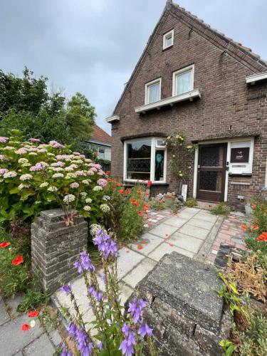 a brick house with flowers in front of it at 22up Bed & Koffie in Den Burg