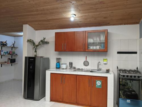 eine Küche mit Holzschränken und einem Kühlschrank aus Edelstahl in der Unterkunft Casa GO in Suesca