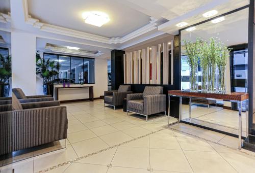 a lobby with chairs and a table and windows at Sandri City Hotel in Balneário Camboriú