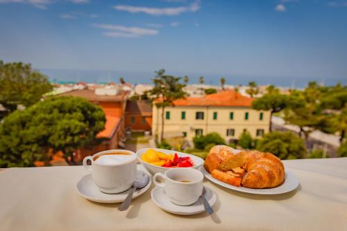 a table with two cups of coffee and croissants at Hotel Belvedere in Forte dei Marmi
