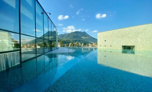 ein Schwimmbad in einem Gebäude mit Bergen im Hintergrund in der Unterkunft Hôtel Rallye & Entrées aux Bains de la Gruyère in Bulle