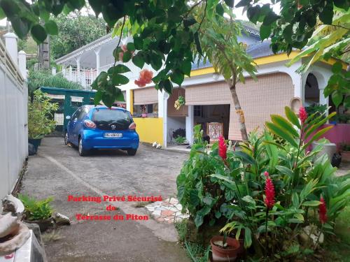 a blue car parked in the driveway of a house at TERRASSE DU PITON in Deshaies