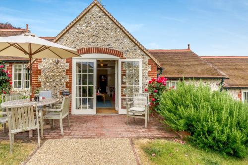 a brick house with a patio with an umbrella at Thyme Cottage in East Dean