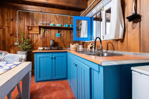 - une cuisine avec des placards bleus et un évier dans l'établissement Cabin in front of idyllic majanicho beach, à Majanicho